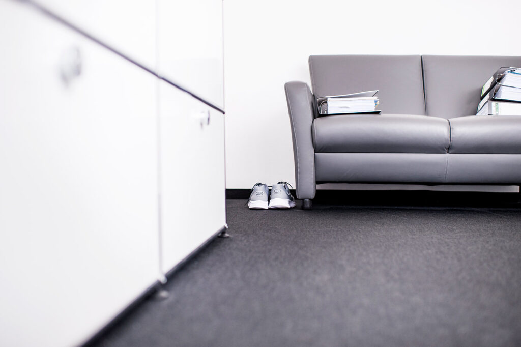 Eine Couch mit Aktenordnern im Büroraum und Sportschuhen